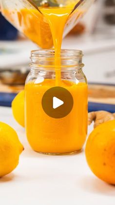 a glass jar filled with orange juice next to lemons