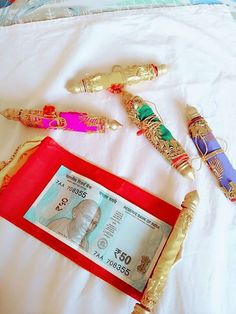 three different types of pens sitting on top of a white bed next to a money bill