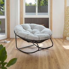 a chair that is sitting in the middle of a room with wood floors and windows