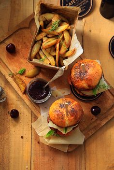 two burgers and some fries on a cutting board