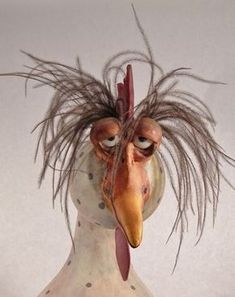 a ceramic sculpture of a chicken with feathers on it's head and eyes open