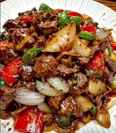 a white plate topped with meat and veggies on top of a wooden table