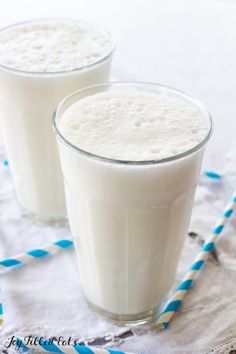 two glasses filled with milk sitting on top of a table