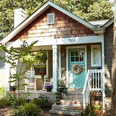 a small house with a blue door and steps leading up to the front porch area