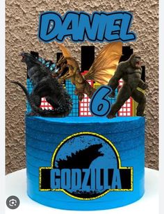 a blue cake with godzilla figurines on top and the words gonzoloa above it