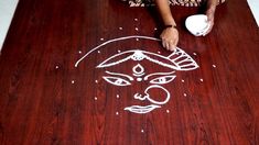 a woman sitting at a table with a drawing on the floor next to her face