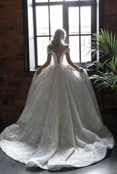 a woman in a wedding dress looking out the window