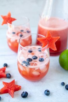 two glasses filled with ice and blueberries next to limes, lemon wedges and star shaped strawberries