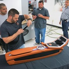 a group of men standing around a table with an orange case on top of it