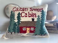 a decorative pillow with the words cabin sweet cabin on it and pine trees in the background