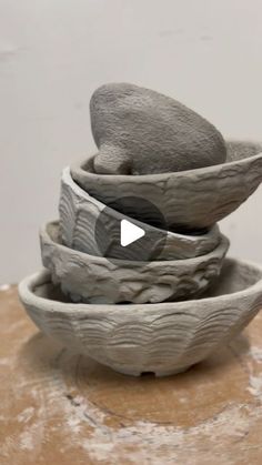 three bowls stacked on top of each other with rocks in the middle and one sitting on top of another bowl