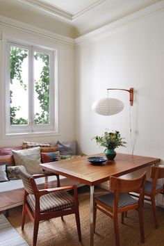 a room with a table, chairs and a couch next to a window in it