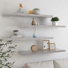 two white shelves with vases and pictures on them next to a couch in a living room