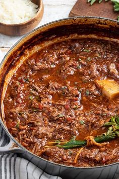 a large pot filled with meat and vegetables on top of a table next to rice