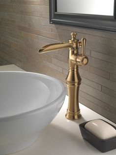 a gold faucet sitting on top of a white sink next to a mirror