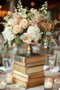 a table topped with books and flowers on top of a white table cloth next to candles