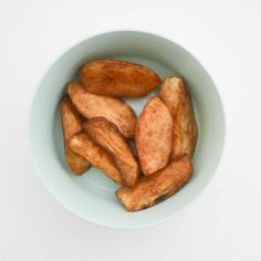 a white bowl filled with fried potatoes on top of a table