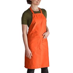 a woman wearing an orange apron and smiling at the camera with her hands on her hips