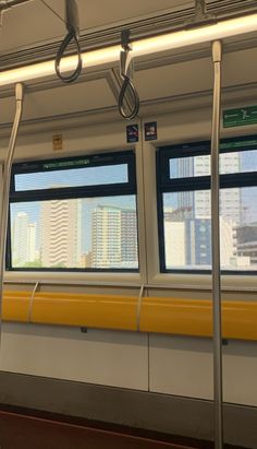 the interior of a subway car with windows and bars on each side, looking out at city skylines