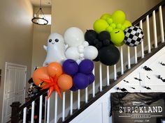 some balloons are hanging on the banister in front of a staircase decorated with halloween decorations