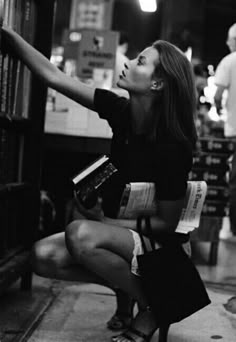 a woman sitting on the floor in front of a bookshelf and looking up