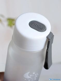 a white bottle with a black lid and a silver clip on the side that says smile