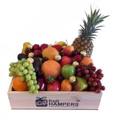 a wooden box filled with lots of different types of fruit next to a pineapple