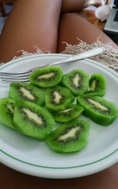 a white plate topped with kiwi slices next to a fork