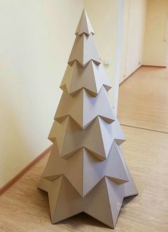 an origami christmas tree sitting on the floor in front of a white wall