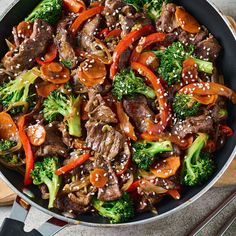 beef and broccoli stir fry in a skillet with chopsticks on the side