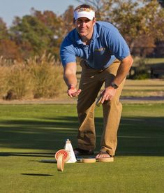 a man standing on top of a green field next to a white frisbee