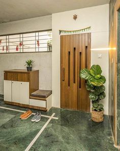 a room with green marble flooring and wooden door, plant in the corner next to it