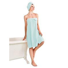 a woman standing next to a bath tub wearing a towel on top of her head