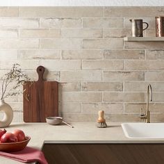 a bowl of apples sitting on top of a counter next to a sink and cutting board