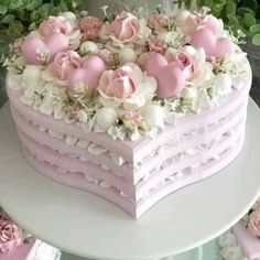 a heart shaped cake decorated with pink and white flowers