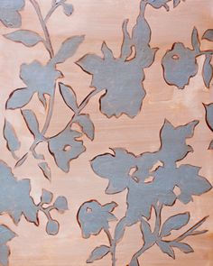 a painting with flowers painted on it in brown and blue colors, sitting on a wooden surface