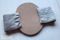 a pair of silver and white mittens sitting on top of a piece of cardboard