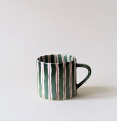 a striped coffee cup sitting on top of a white table