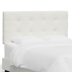 a bed with white linens and pillows on top of the headboard is shown