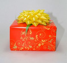 an orange gift box with a yellow bow on it's top and decorative designs