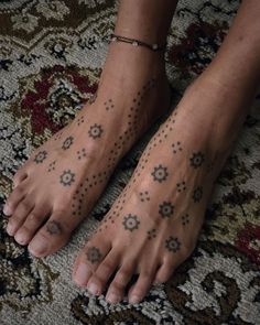 a person with tattoos on their feet sitting on a rug