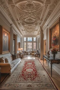 an ornately decorated living room with couches and paintings on the walls, along with a red rug