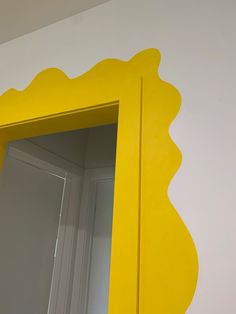 a yellow mirror sitting on the side of a wall next to a white door and window