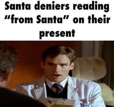 a man sitting at a table in front of a sign that says santa demiers reading from santa'on their present