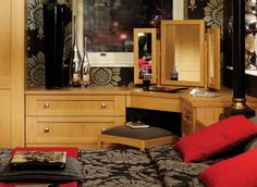 a bed room with a neatly made bed and dressing table next to a mirror on the wall