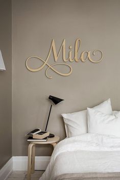 a white bed sitting under a wooden name sign