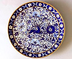 a blue and white plate sitting on top of a table next to a wall mounted clock