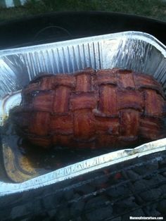 a large piece of meat sitting on top of an open bbq grill with tin foil