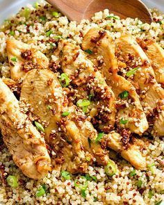 a bowl filled with rice and chicken next to a wooden spoon on top of it