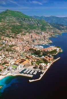 an aerial view of a large city next to the ocean with mountains in the background